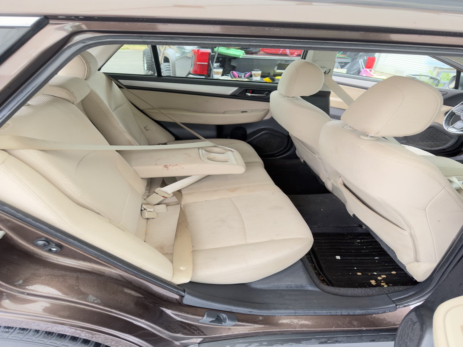 Subaru back seat before detailing, debris on the floor and clutter in the cabin