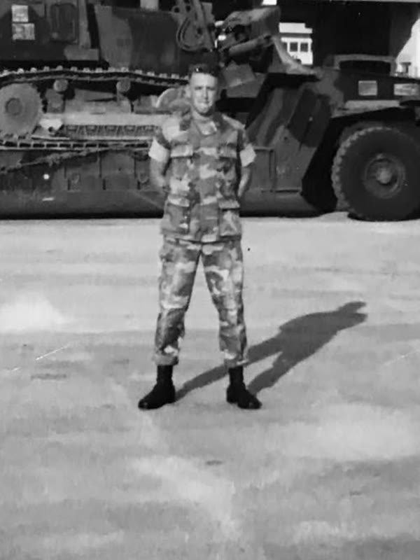 Chuck's father in utilities in front of Marine Corps seven-ton trucks